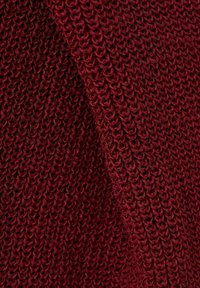 Prim-plan al unei țesături tricotate moi, de culoare burgundy închis, cu un model complicat de ochiuri buclate care creează o suprafață texturată.