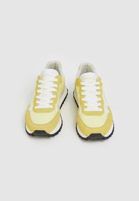 Gula och vita sneakers med snörning, i mocka och mesh-material, rundad tå, svart gummisula och logodetalj på tungan.