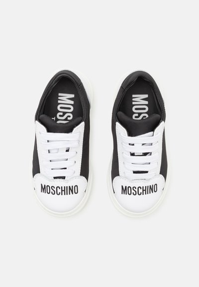 Zapatillas en negro y blanco con un upper de textil suave, cordones en contraste y llamativo branding de "MOSCHINO" en las punteras.