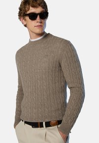 Beiger Rippstrickpullover mit Rundhalsausschnitt, langen Ärmeln und strukturiertem Muster. Tragen Sie ihn mit cremefarbenen Hosen und einem schwarzen geflochtenen Gürtel.