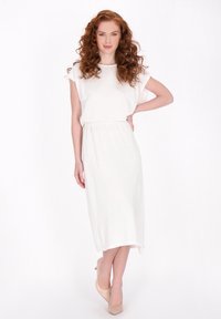 Witte jurk tot op de knie met korte mouwen en een cinched taille. Zachte textuur en een ontspannen silhouet. Draag met nude hakken.