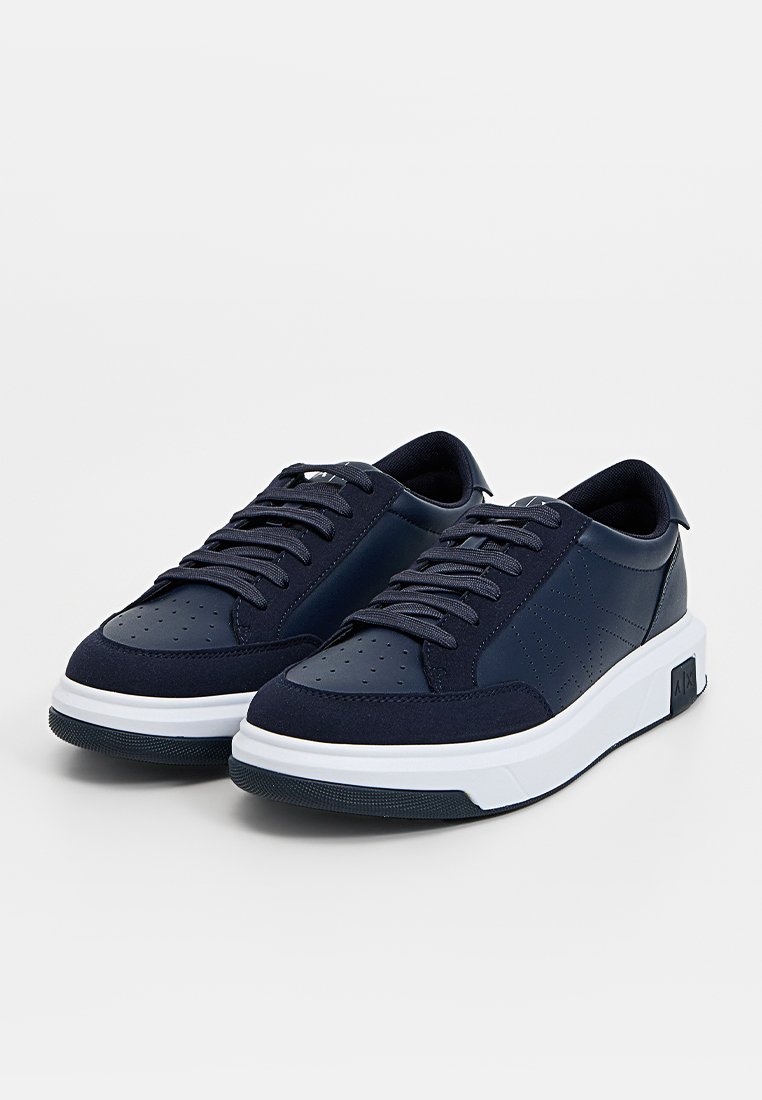 Sneakers blu navy con tomaia sintetica liscia, punta forata, lacci tondi e suola intermedia bianca. Accenti testurizzati e logo sul tallone.