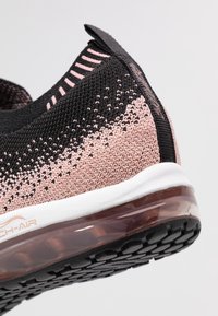 Sportskor med övre del i svart och rosa stickat med gradientstruktur, vit mellansula och en transparent luftpumpsula.