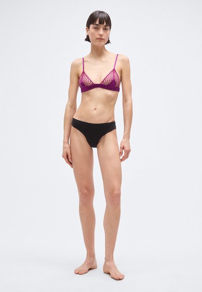 Fioletowy biustonosz typu bralette w kształcie trójkąta z detalami z siateczki, w zestawie z czarnymi majtkami. Posiada cienkie ramiączka i prosty design, odpowiedni na strój kąpielowy.