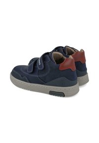 Zapatillas azul marino con acentos de ante y cuero, tiras de Velcro, suela de goma gris y detalle del talón en rojo contrastante.