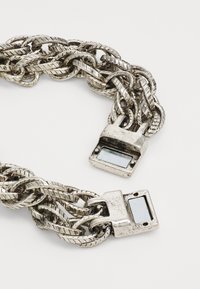Silver chain necklace with braided links and rectangular metal clasps featuring a flat surface. Glossy and textured design details present.