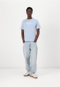 Ανοιχτό μπλε βαμβακερό μπλουζάκι με στρογγυλή λαιμόκοψη, με λευκό κείμενο "Pepe Jeans London". Συνδυάζεται με αέρινα ανοιχτόχρωμα τζιν και αθλητικά παπούτσια.