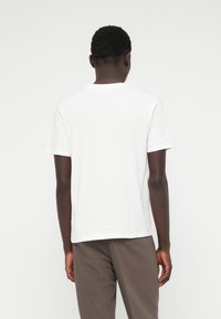 Biele bavlnené tričko s klasickým okrúhlym výstrihom, krátkymi rukávmi a rovný strih. Hladká textúra, bez viditeľných vzorov alebo akcentov.