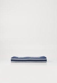 Marineblå, sammenfoldet håndkle med hvite striper, laget av mykt stoff. Har en flat, rektangulær form med pent sydd kant.