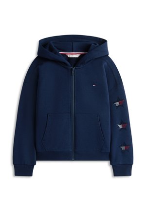 Μπλε ναυτικού φερμουάρ φούτερ με εμπρός τσέπες, μικρό λογότυπο στο στήθος και τρία κόκκινα, λευκά και μπλε μπαλώματα αστεριών στο δεξί μανίκι.