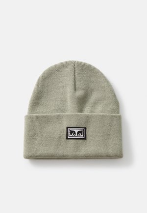 Knit beanie in light green with a folded cuff and a black logo patch featuring white accents. Soft texture and simple design.