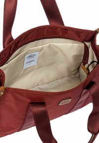 Grand sac fourre-tout bordeaux ouvert avec doublure beige à l'intérieur, larges sangles pour l'épaule et une petite étiquette interne affichant des informations sur la marque et le tissu.
