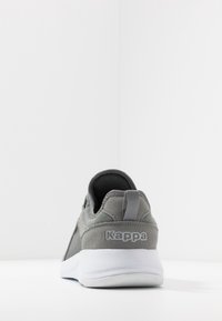 Grå Kappa sneaker set fra bagsiden, med en hvid sål og stofpull-tab på hælen, placeret mod en plain hvid baggrund.