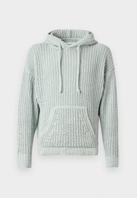 Sudadera de punto verde claro con un corte holgado, cordones y un bolsillo delantero. La textura es gruesa, lo que proporciona una apariencia transpirable.