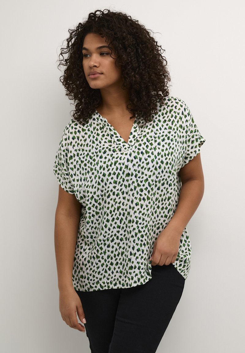 Blusa corta a maniche corte verde e bianca con scollatura a V, caratterizzata da un motivo a macchie di leopardato sparse e una vestibilità rilassata e ampia.