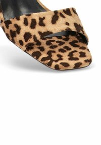 Zapato de tacón abierto con estampado de leopardo que presenta una correa de acento negra, hecho de suave gamuza con una plantilla negra lisa y una punta cuadrada.