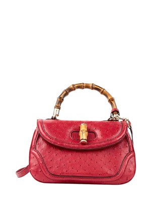 Sac à main en cuir rouge texturé avec poignée en bambou courbée et fermeture à fermoir en bambou sur rabat, sur fond blanc.