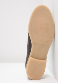 Sneaker marrone con una tomaia testurizzata, dettagli in mesh e una suola in gomma naturale. Taglia 37 riportata sulla suola.