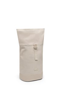 Tall beige roll-top backpack with front buckle strap and small rectangular brand label near bottom.