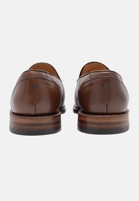 Bruine leren schoenen met een gladde afwerking, ronde neus en een gestapelde houten hak. Kenmerkend zijn de minimale stiksels en een klein logo op de hak.