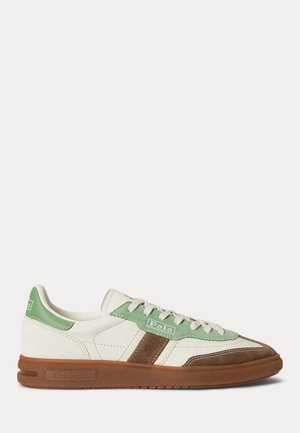 Lavtopet sneaker i hvidt læder med grønne og brune ruskindsdetaljer, hvide snørebånd og en brun gummisål.