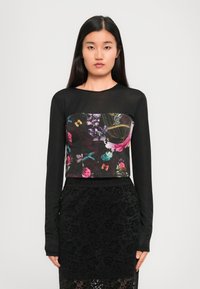 Black long-sleeve top with a floral design in vibrant colors, paired with a black lace skirt featuring a floral pattern and an elastic waistband.