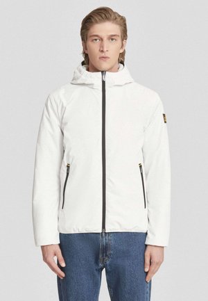 Giacca isolante bianca con chiusura frontale a zip, cappuccio regolabile e due tasche laterali con zip. Presenta rifiniture nere e un logo in evidenza.