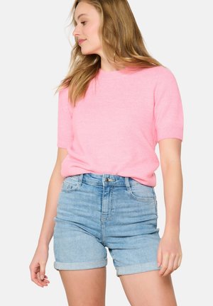 Rosa kurzärmeliger Strickpullover mit rundem Ausschnitt, kombiniert mit hellblauen Denim-Shorts mit umgeschlagenen Säumen und vorderen Taschen.