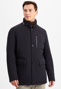 Schwarze isolierte Jacke mit hohem Kragen, Frontknöpfen, zwei großen Taschen und einer mit Reißverschluss versehenen Brusttasche mit glatter Textur.