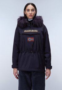 Mörkblå parkajacka med fuskpäls på huva, dragsko i midjan, framfickor med dragkedja och broderad norsk flagga. Elastiska ärmslut och slitstukt tyg.