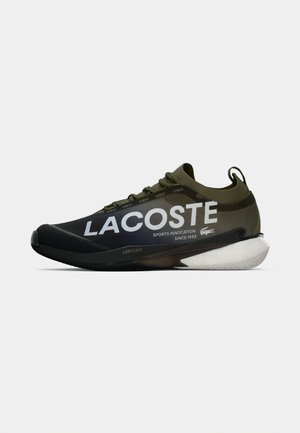 Scarpa atletica Lacoste in verde scuro e nero con branding bianco. Presenta materiale sintetico liscio, lacci testurizzati e suola in schiuma.