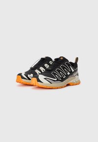 Black and gray athletic shoes with a lightweight design, featuring orange soles and reflective accents, designed for outdoor activities.