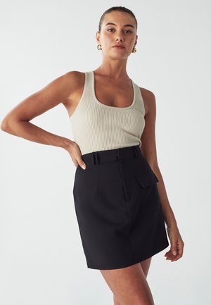 Gestreept beige tanktop gecombineerd met een hoge taille, zwarte korte rok met een patchzak en een ceintuurlijf. Soepele textuur, aansluitende pasvorm.