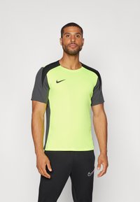 Camiseta Nike con cuerpo en verde neón y mangas grises, mangas cortas, cuello redondo y logo en el frente. Material de poliéster.