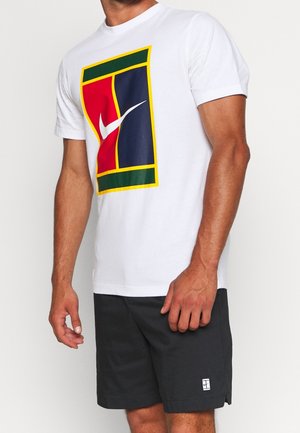 Homme portant un t-shirt blanc avec un logo Nike rouge, bleu, vert et jaune et un short noir avec un petit logo blanc sur la jambe gauche.