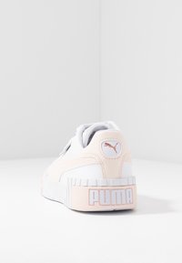 PUMA-sneakers med en vit och ljus rosa färgskala, överdel i slätt läder, vadderad krage och framträdande varumärkeslogo på hälen.