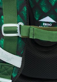 Plecak wykonany z zielono-czarnej tkaniny w geometryczny wzór, z regulowanymi zielonymi paskami oraz białymi akcentami logo na fakturowej powierzchni.