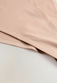 Lichtbeige stof met een gladde textuur, voorzien van een scherpe rand en subtiele glans. De vorm is plat met nauwkeurige stiksels.