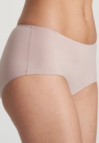 Bañador hipster de color rosa claro, hecho de un material suave y elástico. Presenta un diseño sin costuras y un corte minimalista. Sin herrajes ni patrones visibles.