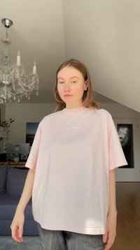 Per didelė rožinė marškinė su trumpomis rankovėmis ir grublėtu apykakle. Priekyje yra subtilus balto logo. Minkšta medvilninė tekstūra.