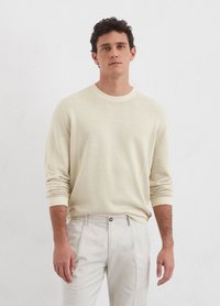 Cream sweater with a round neck, long sleeves, and ribbed cuffs, paired with light-colored trousers, against a plain white background.