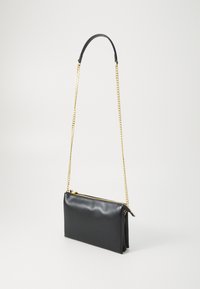 Borsa a tracolla in pelle nera con catena dorata, chiusura a zip e una superficie liscia. Forma rettangolare con un design minimalista.