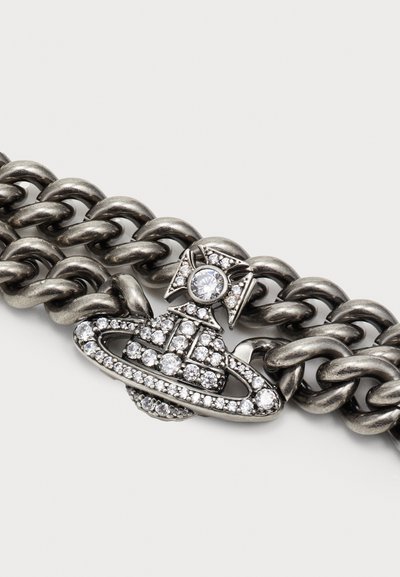Bracciale in metallo a catena con un elemento decorativo centrale impreziosito da strass trasparenti, finitura argento antico e un accentuato fiocco.