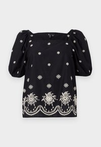 Blusa nera a taglio ampio con maniche a sbuffo. Presenta ricami floreali bianchi e una rifinitura decorativa lungo il fondo. Scollatura quadrata.