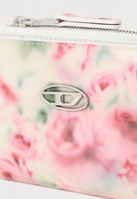 Πορτοφόλι με λουλουδάτο μοτίβο σε απαλούς παστέλ τόνους, κατασκευασμένο από λεία συνθετική ύλη και αξεσουάρ σε ασημί απόχρωση με λογότυπο.