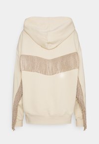 Sudadera beige con capucha, con detalles de flecos metálicos en la parte trasera y los costados, de textura suave y ajuste holgado.