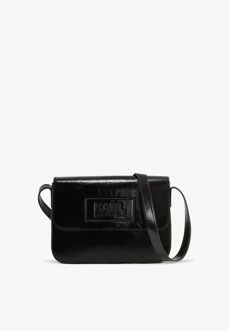 Svart läder crossbody-väska med en slät yta, klaffstängning, präglad logotyp och justerbar rem. Kompakt rektangulär design.