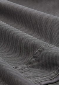 Dark gray fabric with a subtle textured pattern, featuring smooth folds and stitching along the edge, showcasing its durability.