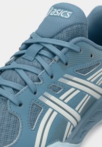 Blå treningssko med mesh og syntetisk materiale, lisser i matchende farge og hvite stripete detaljer på siden.