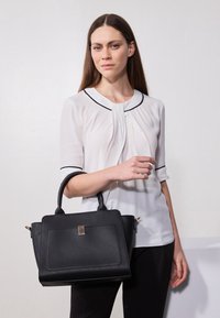 Svart läderhandväska med en strukturerad design, utrustad med handtag upptill, en framficka och detaljer i guld.